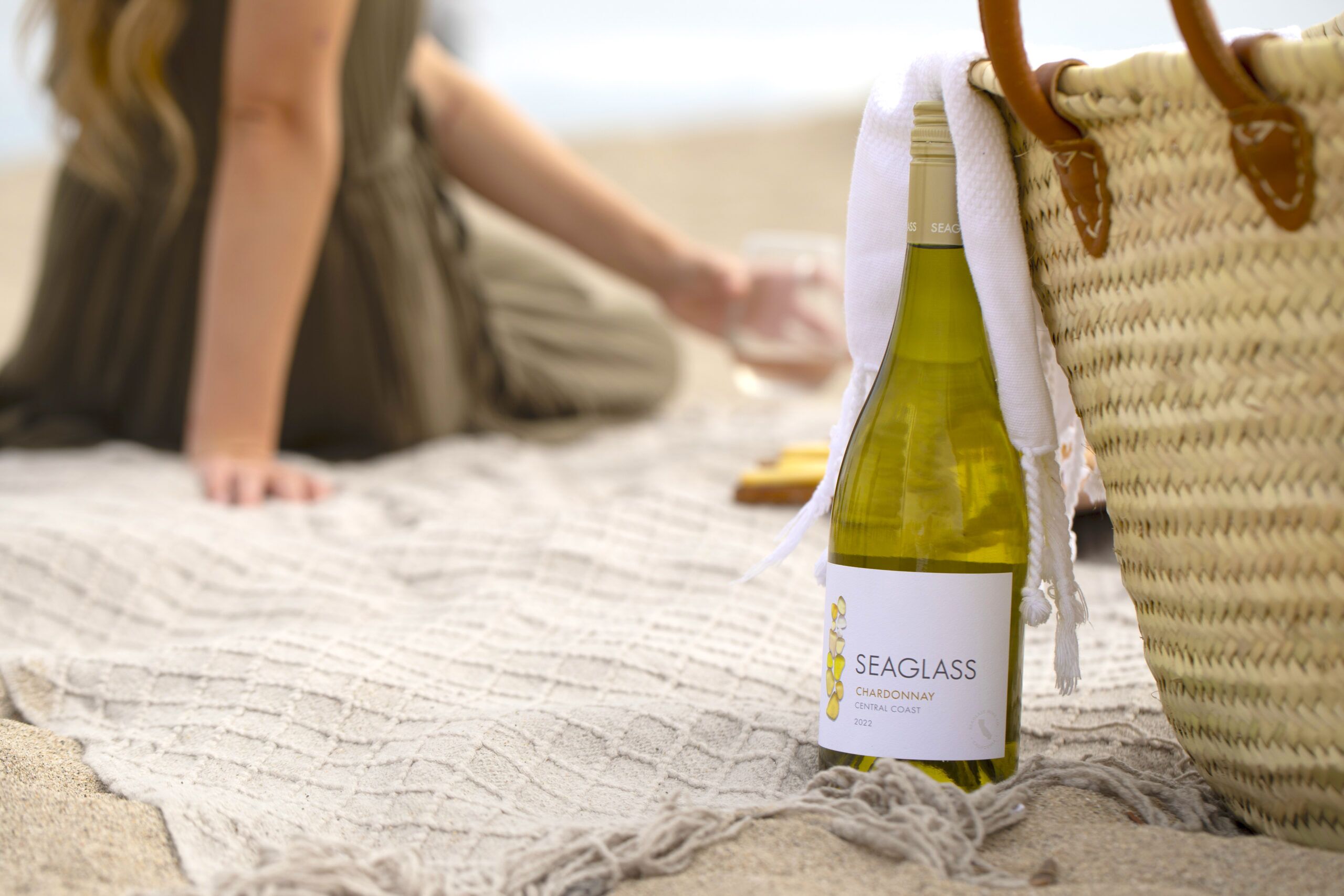 SEAGLASS Chardonnay bottle in sand next to beach bag
