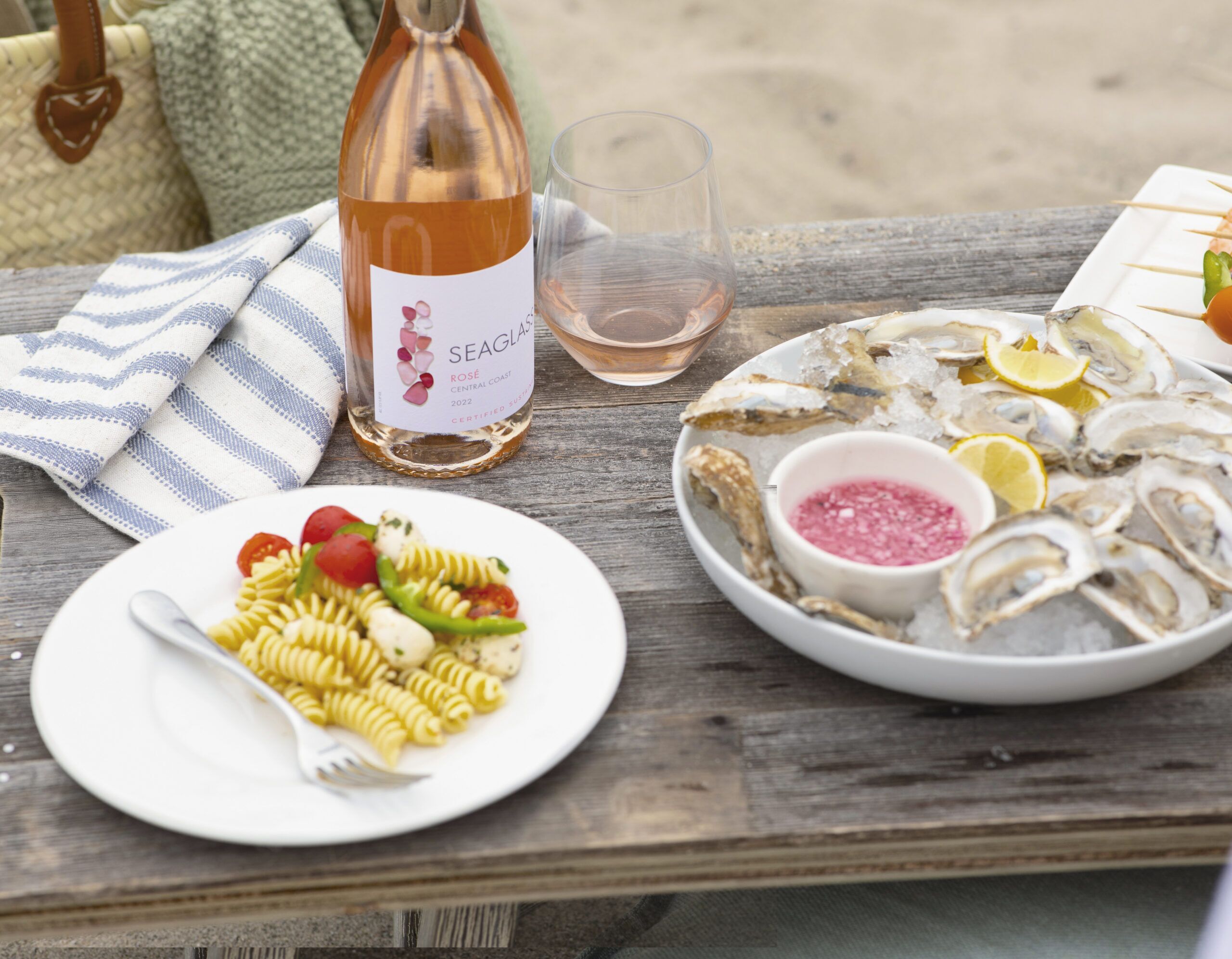 SEAGLASS Rose bottle on table with oysters and pasta