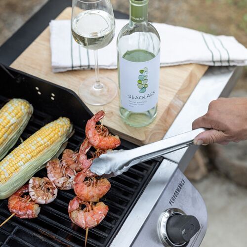 Cooking shrimp and corn on an outdoor grill, with a bottle of Seaglass white wine beside it